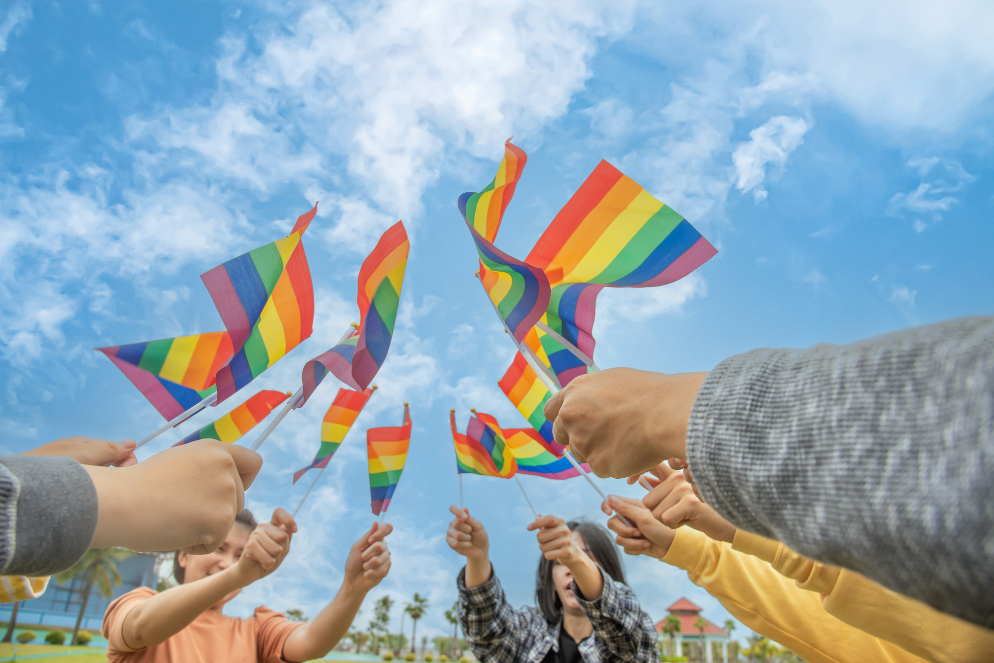 Diversity people hands raising colorful lgbtq rainbow flags together , a symbol for the LGBT community,selective focus.concept LGBTQ community equal movement parade ,LGBTQ pride month.