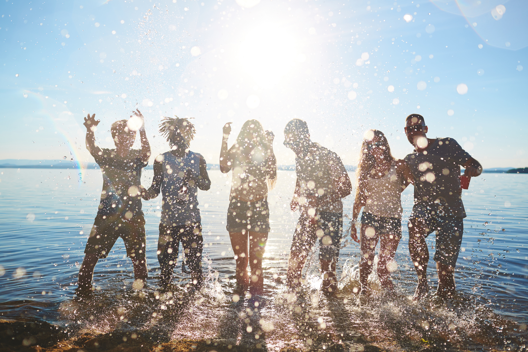 Group of happy young men and women dancing in water