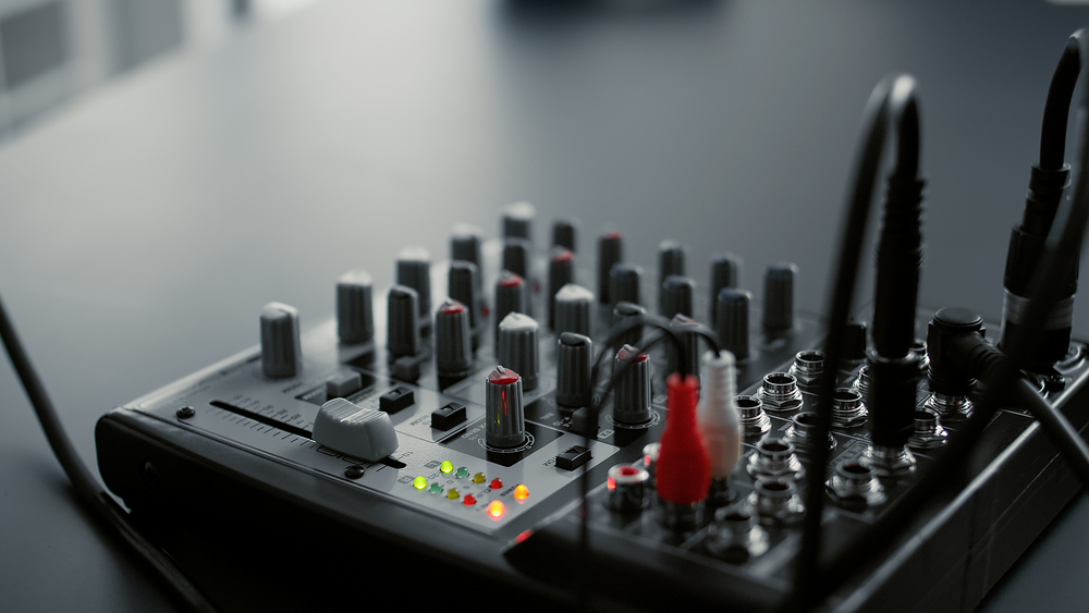DJ mixer console with knobs and equalizer standing on home studio desk. Professional audio sound station electronic controller in living room video recording space. Close up