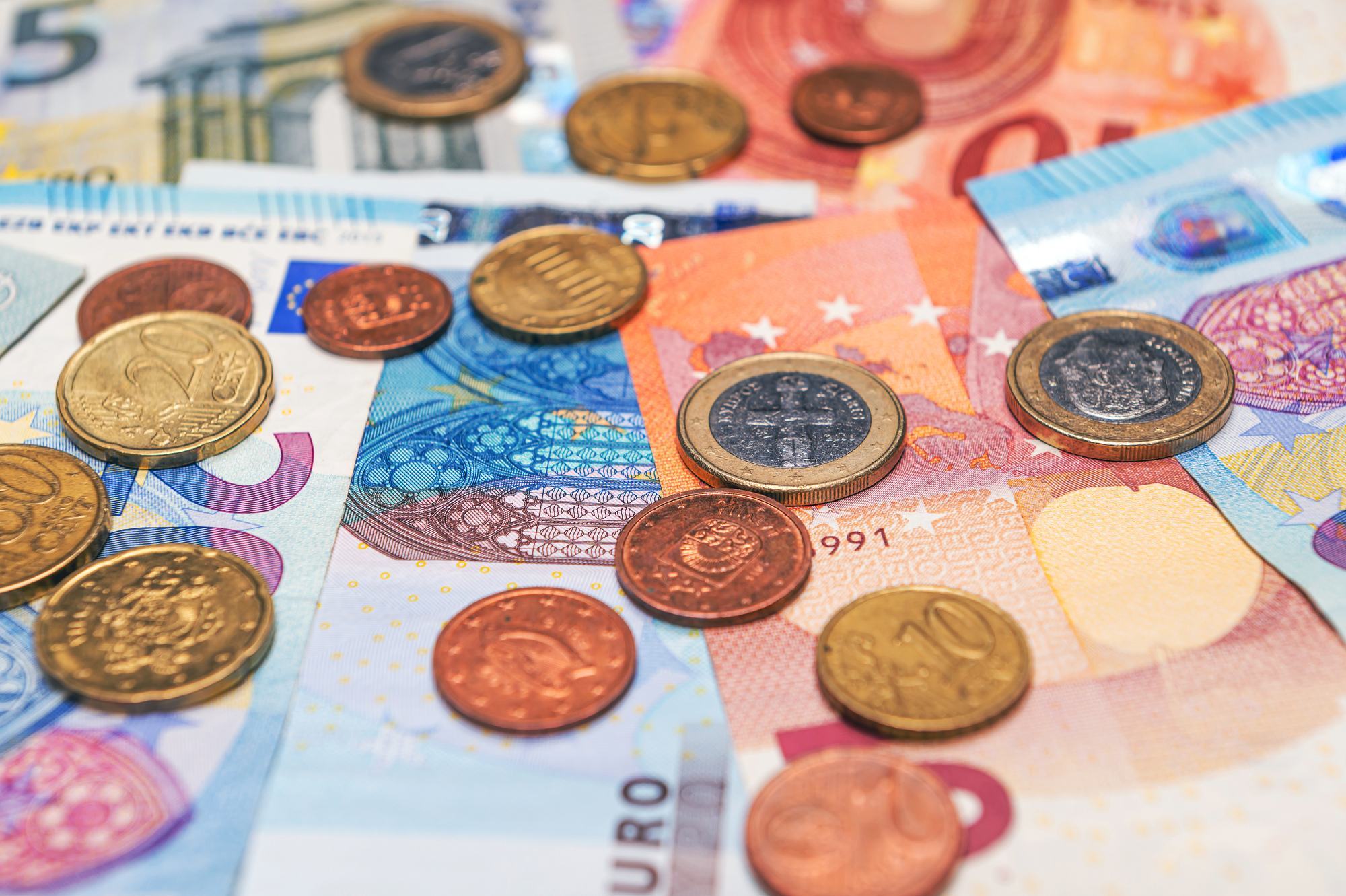 background of banknotes and euro coins of different denominations close-up