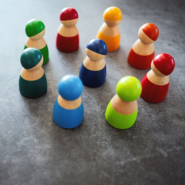 One of wooden figurine standing in the center of a circle among the others for the concepts of diversity, leadership and business
