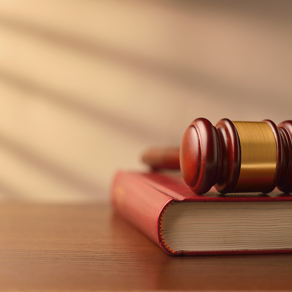 Law book and wooden judges gavel on a wooden table top in a shaft of sunlight with rayed shadow effect, conceptual image of law enforcement with copyspace