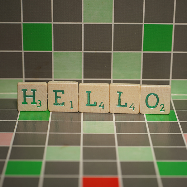 Wooden tile with green hello text on a blocked background